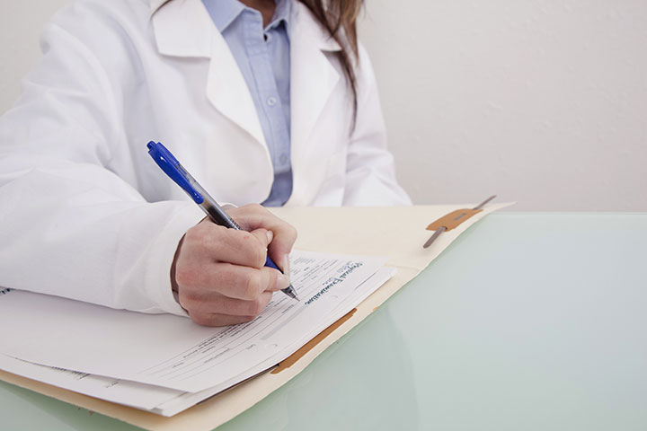 Doctor writing on patient chart.